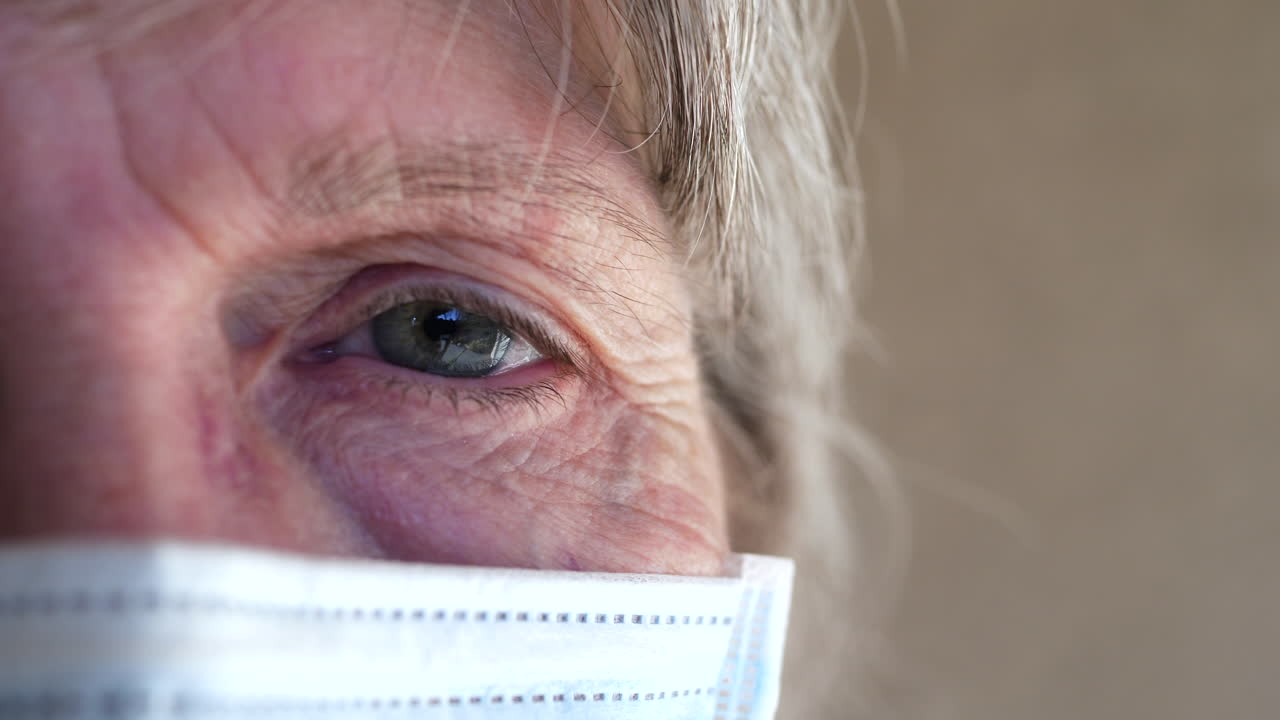 Primo piano del volto e dell'occhio di una donna anziana con una mascherina medica per prevenire la diffusione di una malattia o per non ammalarsi