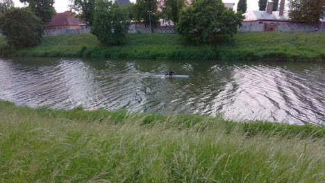 A-man-paddling-a-kayak-on-a-river-flowing-through-the-city-of-Olomouc