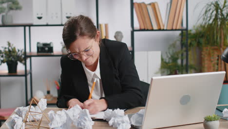 angry furious woman working at home office throwing crumpled paper, having nervous breakdown at work