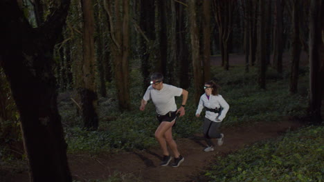 man and woman running on forest trail at dusk