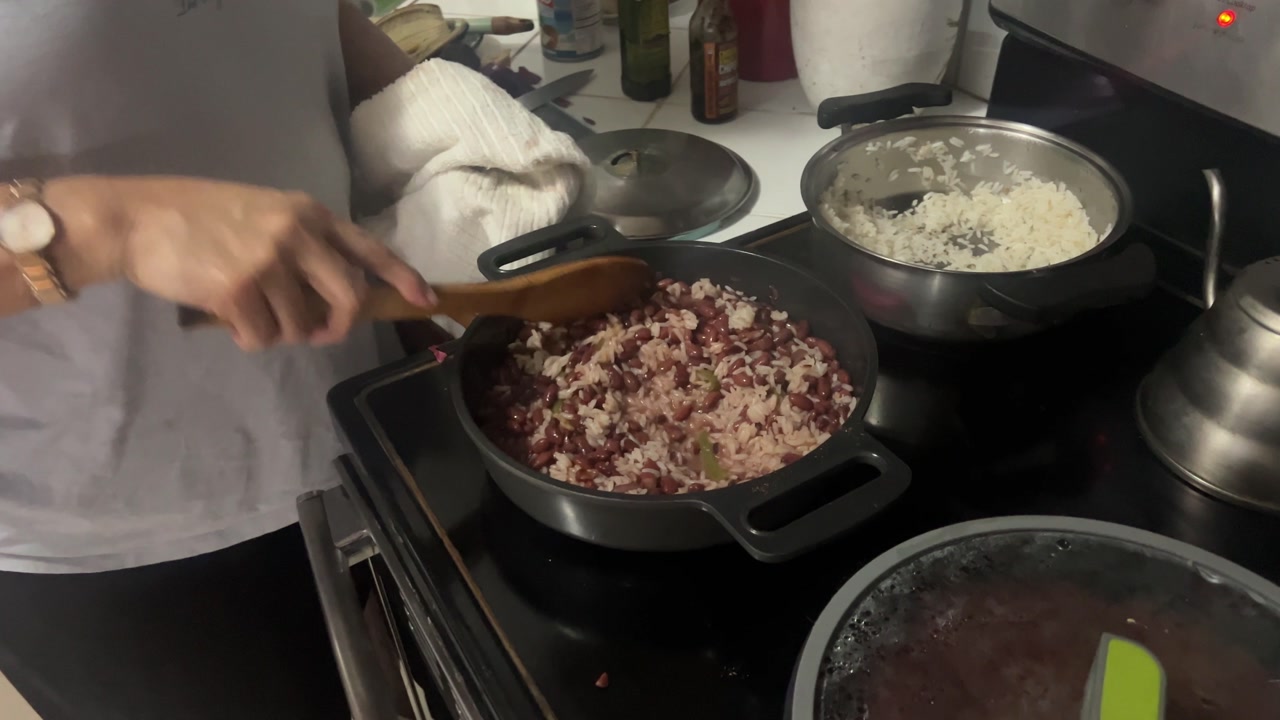 Honduras frijoles con arroz prepared at home, beans mixed with rice in a pan on stove, showing traditional Honduran cooking and everyday local cuisine.