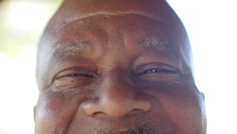 Retrato-De-Ojos-Felices-De-Un-Hombre-Afroamericano-Mayor-En-Una-Terraza-Soleada,-Cámara-Lenta