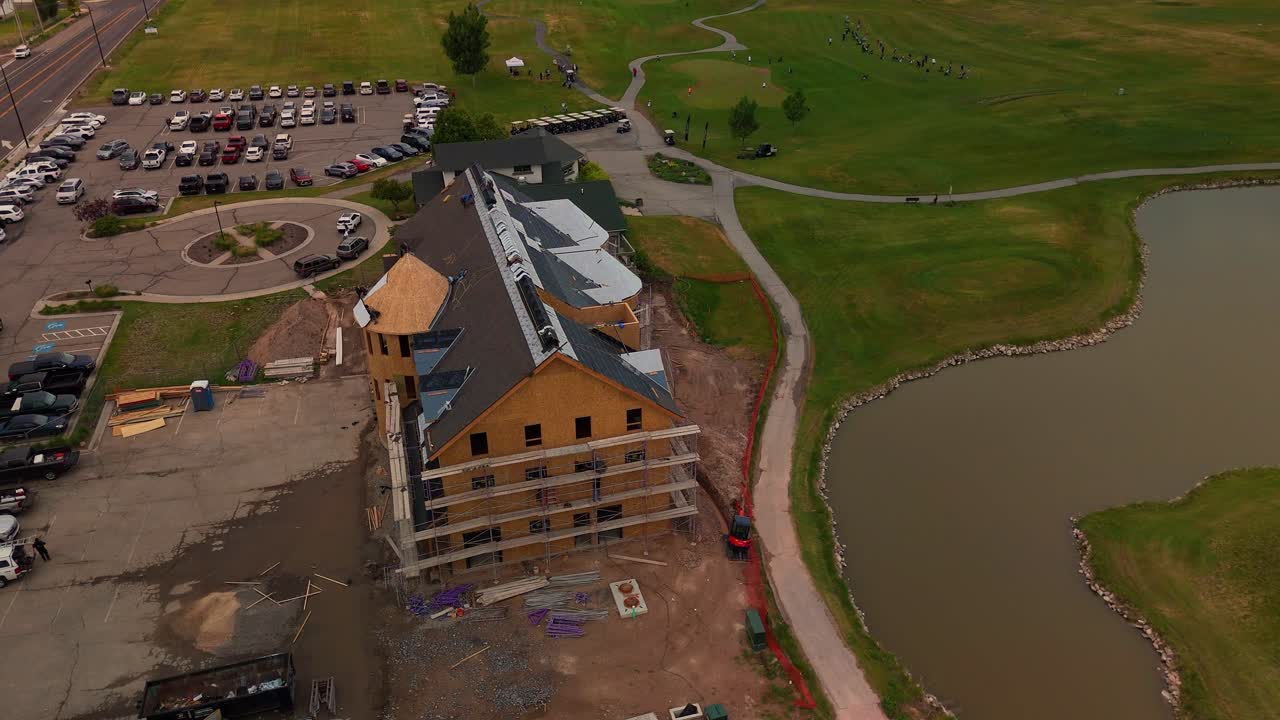 Flying Drone Over PGA Golf Course Clubhouse Construction Site with Workers Laying Roofing on Cloudy Overcast Rainy Spring Day