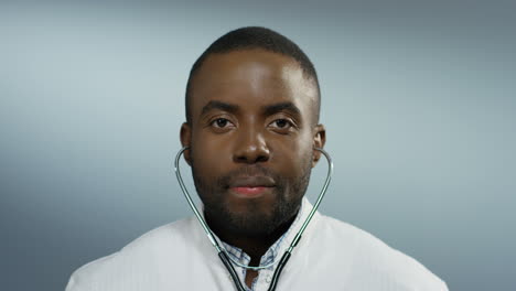 portrait of the young attractive man physician with stethoscope in ears smiling joyfully to the camera