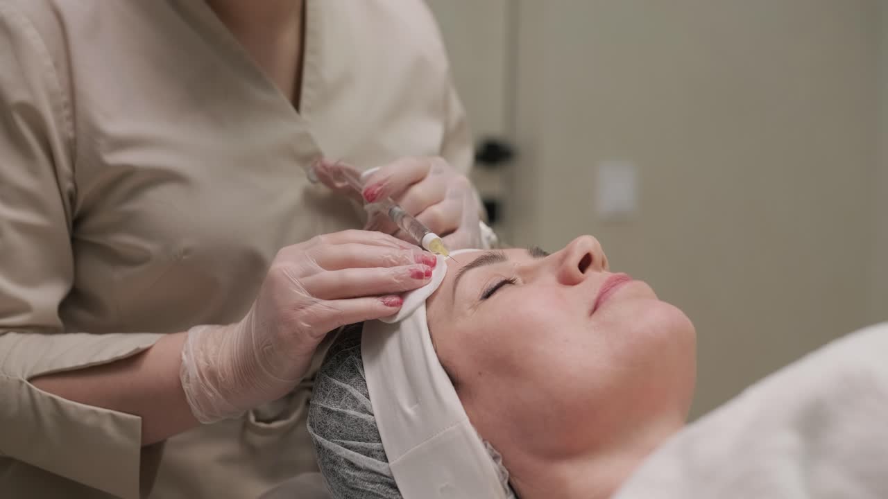 Woman making botulinum therapy in modern cosmetology clinic close up. Professional cosmetologist doing injection with botulinum toxin for rejuvenation face skin. Attractive lady patient smoothing wrinkles.
