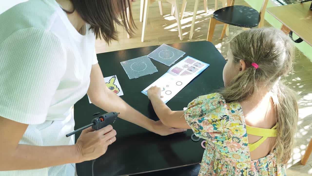 madre e hija haciendo un proyecto de artesanía de cuentas