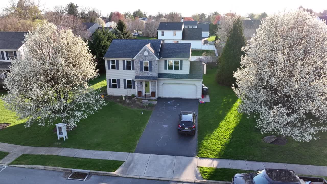 fotografía aérea de una casa con biblioteca al aire libre, tiza de acera y árboles en flor en primavera
