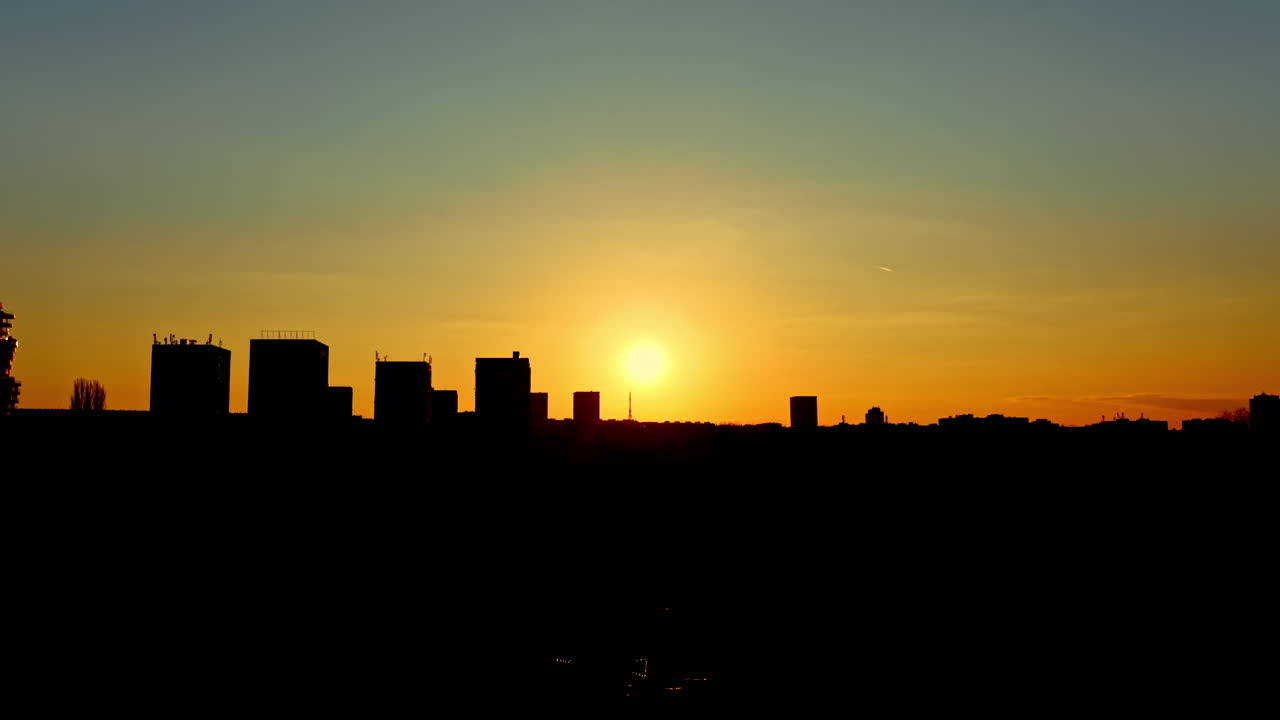 Atardecer sobre el horizonte de una ciudad con edificios silueteados contra el cielo vespertino, que presenta colores brillantes y una luz que se desvanece.