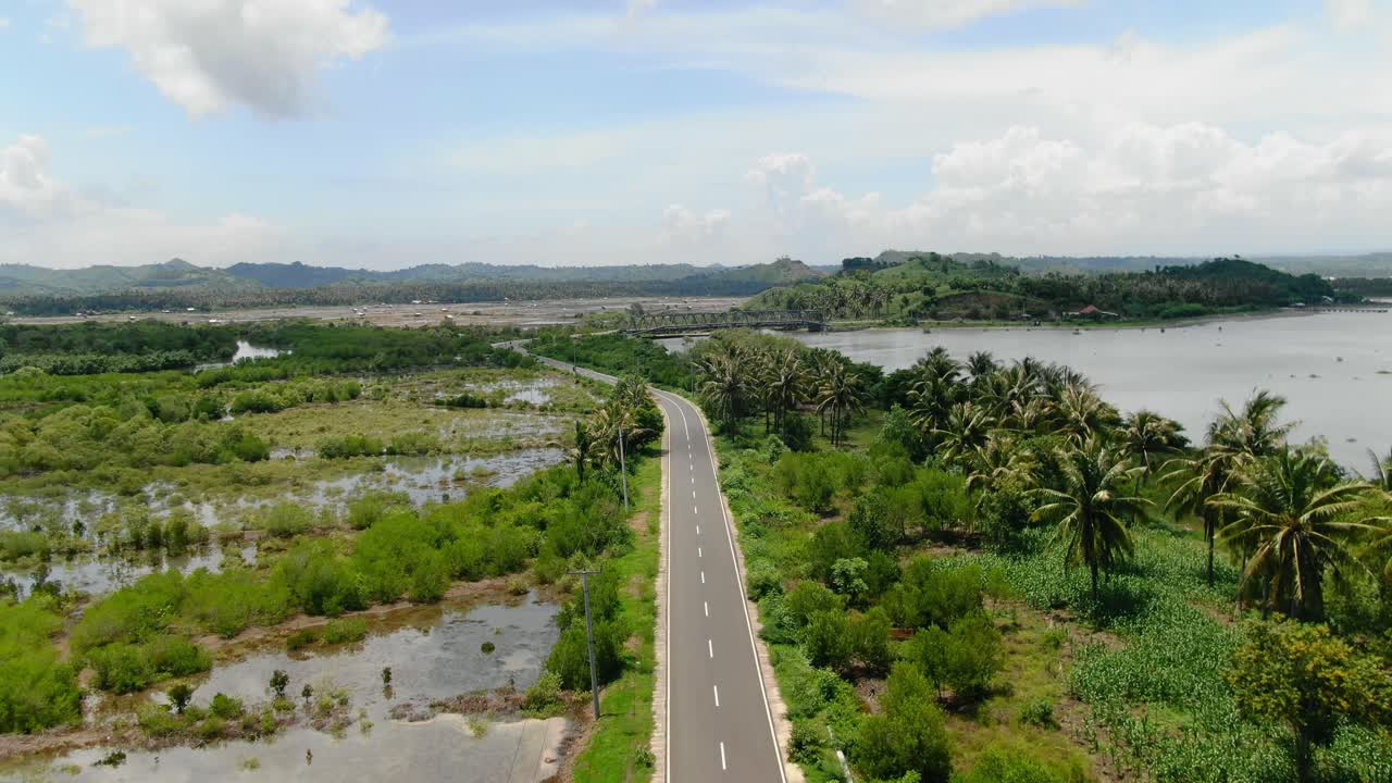 vista aérea que avanza, vista panorámica de la carretera del sur y los campos de arroz, puente que conecta las islas de lombok