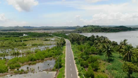 aerial view moving forward shot, scenic view of southern road and rice fields, bridge connecting lombok islands