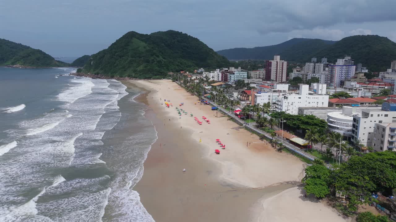 Praia do Tombo Guarujássa, São Paulossa, Brasiliassa, hiekkarannalla, Atlantin valtameren aalloilla, asuinalueen siluetilla ja Atlantin metsän peittämillä Serra do Marin kukkuloilla, vastapäivään kiertäen, yläkuvana ja laajakuvana.
