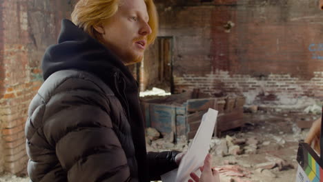 close up view of two production coworkers talking and reading a document about the movie in a ruined building