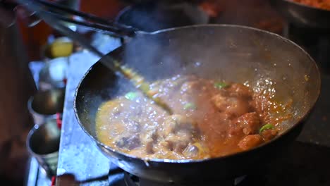 chef stirring hot sizzling curry in wok