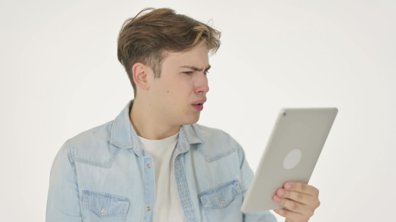 젊은 남자가  바탕의 태블릿에서 손실에 반응하고 있습니다.