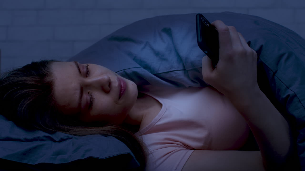 Woman Using Phone in Bed at Night