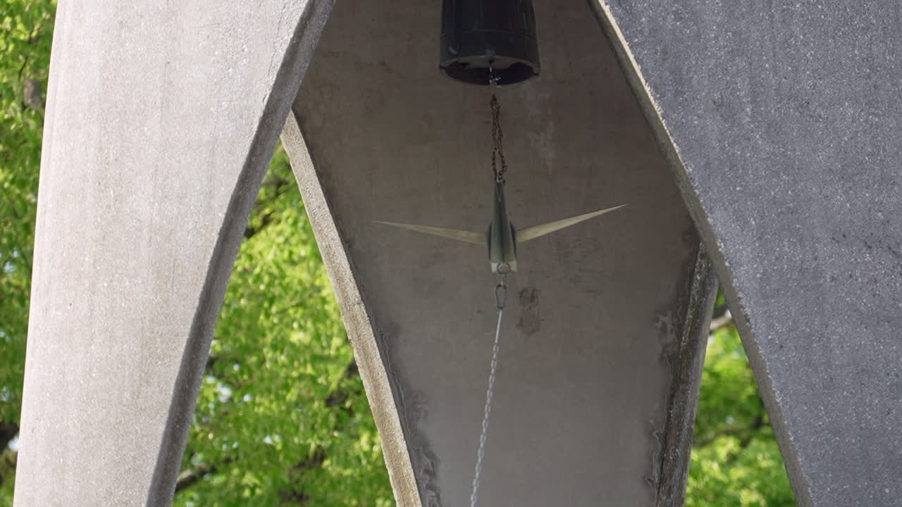 Daytime close-up of the origami-shaped bell at Hiroshima’s Children’s Peace Monument, located in the Peace Memorial Park, as it is being rung. A poignant moment symbolizing hope and remembrance.