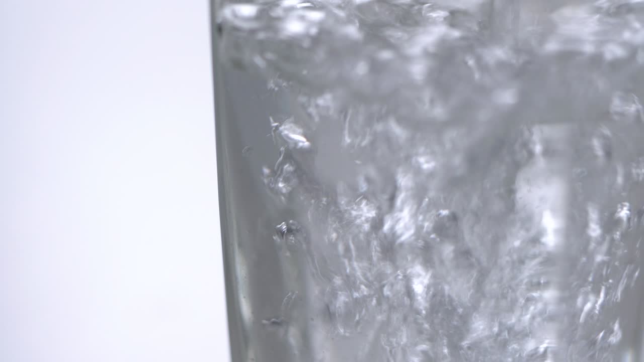 테이블 위에 있는 유리잔에 신선한 미네랄 물을 부어주고, 색 바탕에 산소 공이 있는 신선한 스파클링 음료