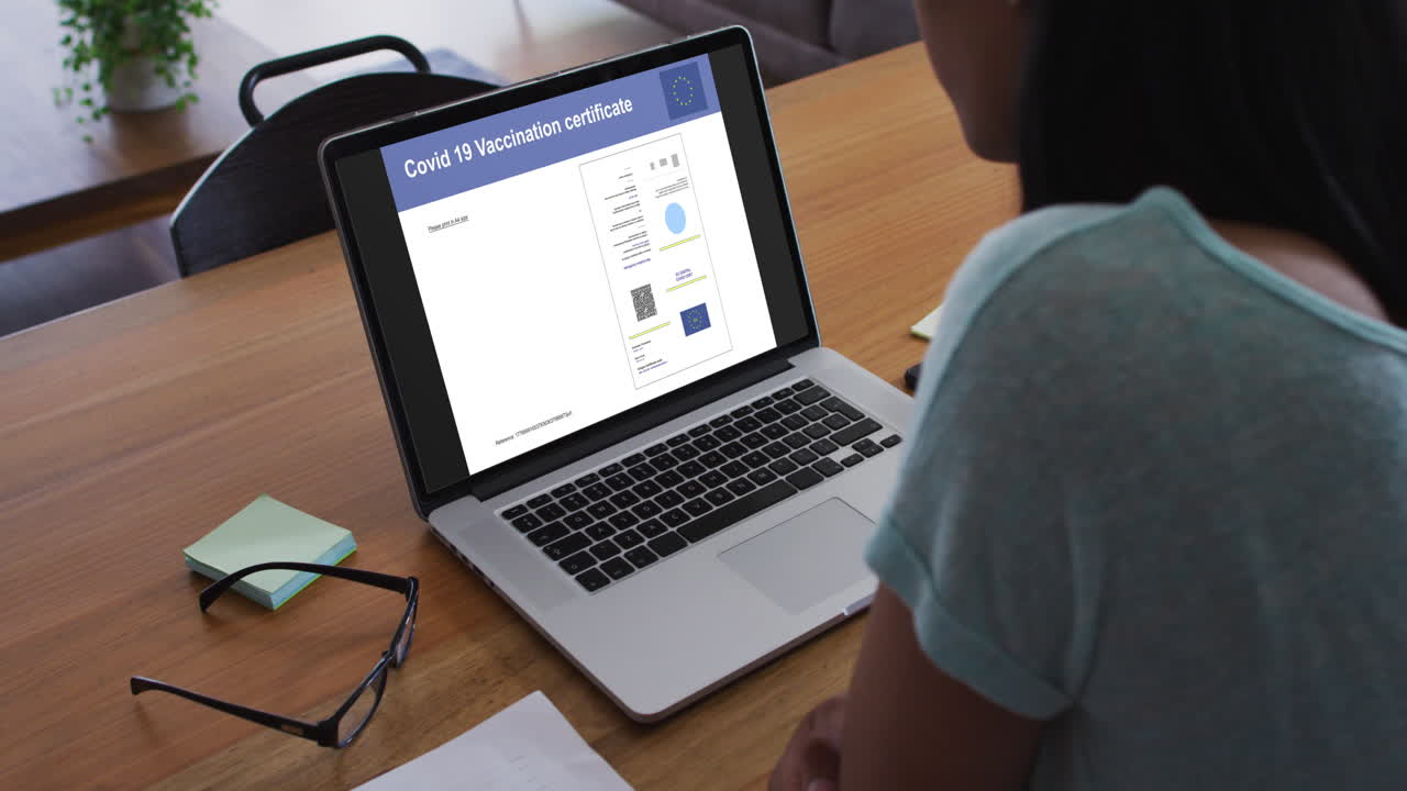 mujer trabajando en el escritorio, certificado de vacunación de covid en la pantalla del portátil