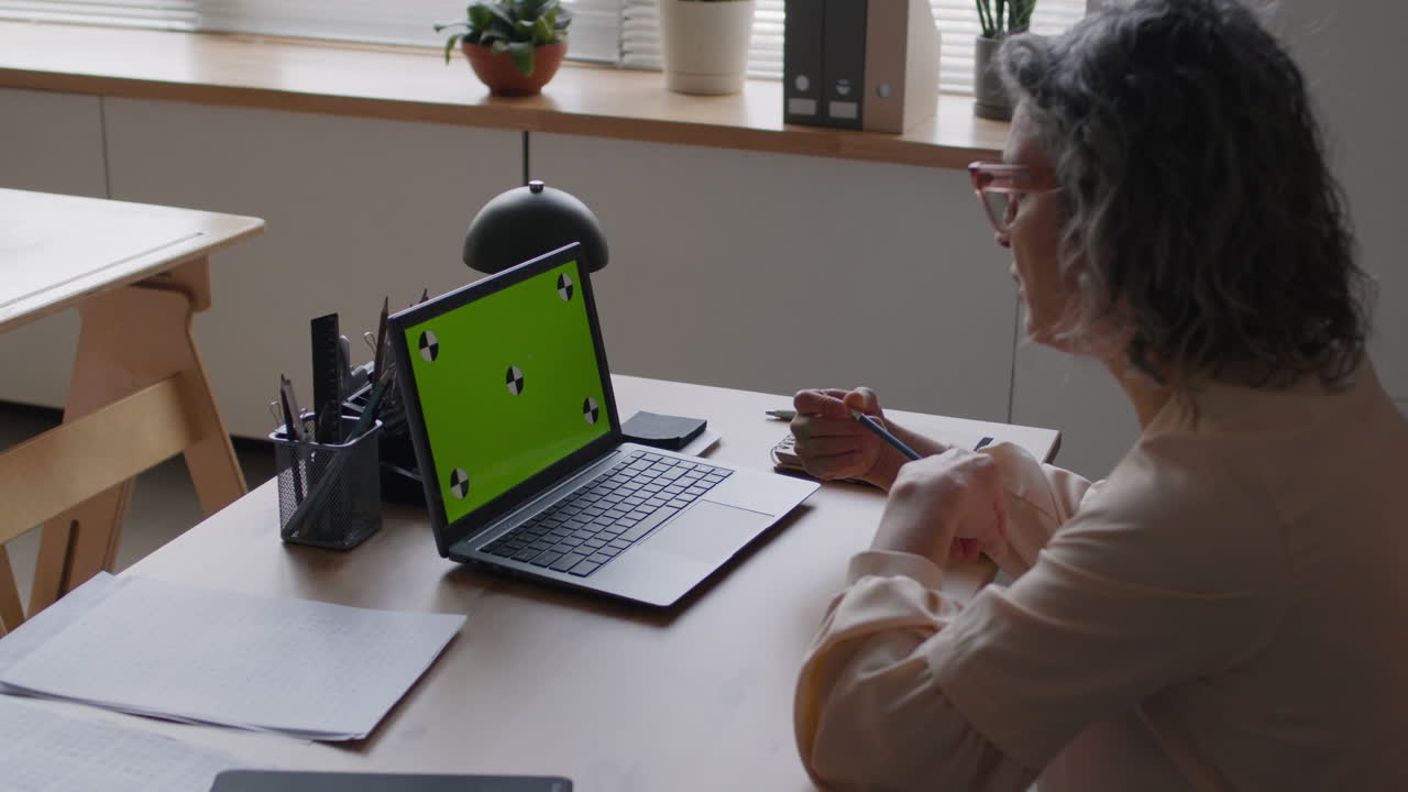 mujer trabajando en una computadora portátil con una pantalla verde