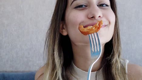 cámara lenta: una hermosa joven muestra comida de pollo en un tenedor con un gran disfrute en un restaurante o cafetería mientras está sentada