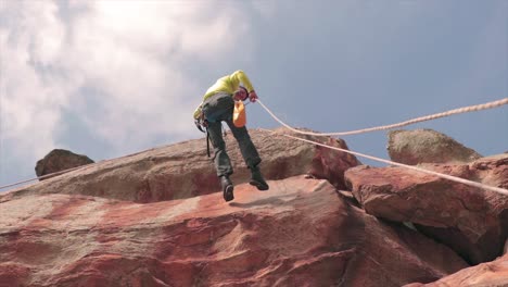 rock climber dropping fast from a rope hanging on a rock