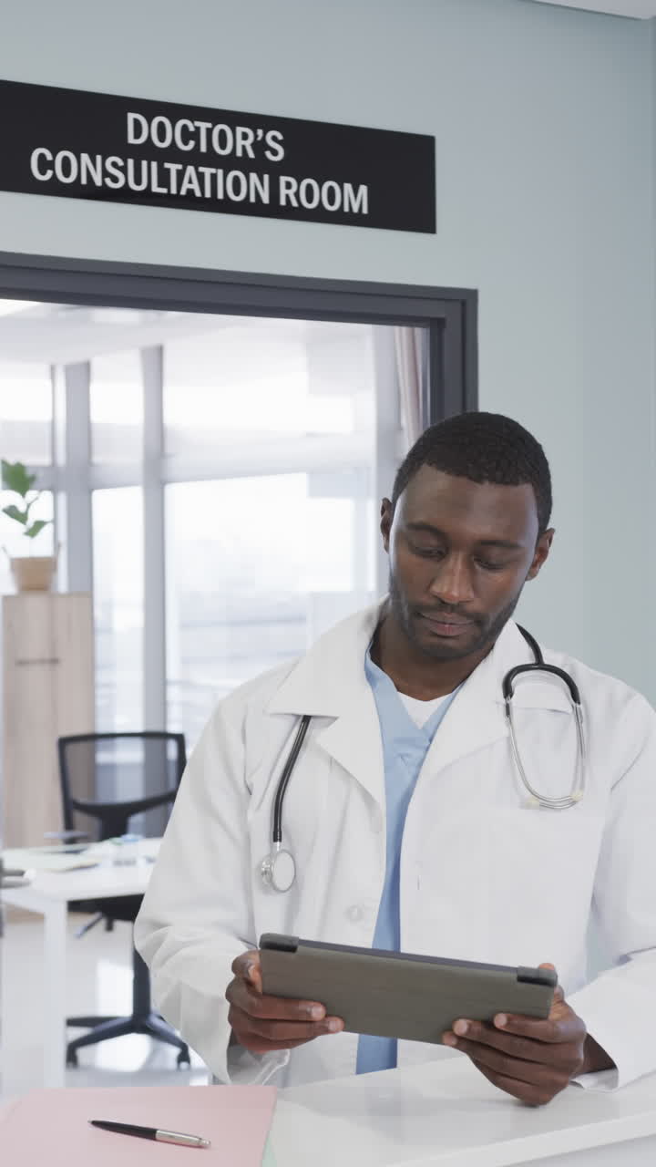 Video verticale di un medico afroamericano felice che usa un tablet in ospedale, slow motion
