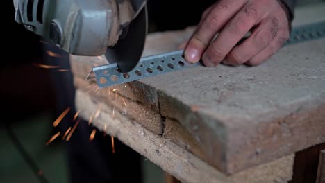 a man holds an angle grinder in his hands and cuts off a metal mount with it.