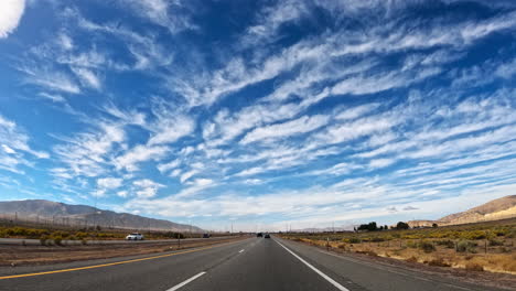 driving towards the mountains on a highway in the mojave desert with altocumulus clouds overhead