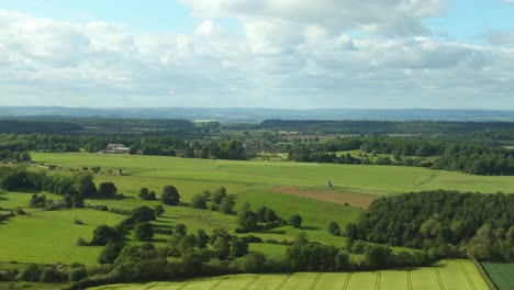 high drone view of british countryside with historical buildings and green fields for miles on sunny but cloudy day