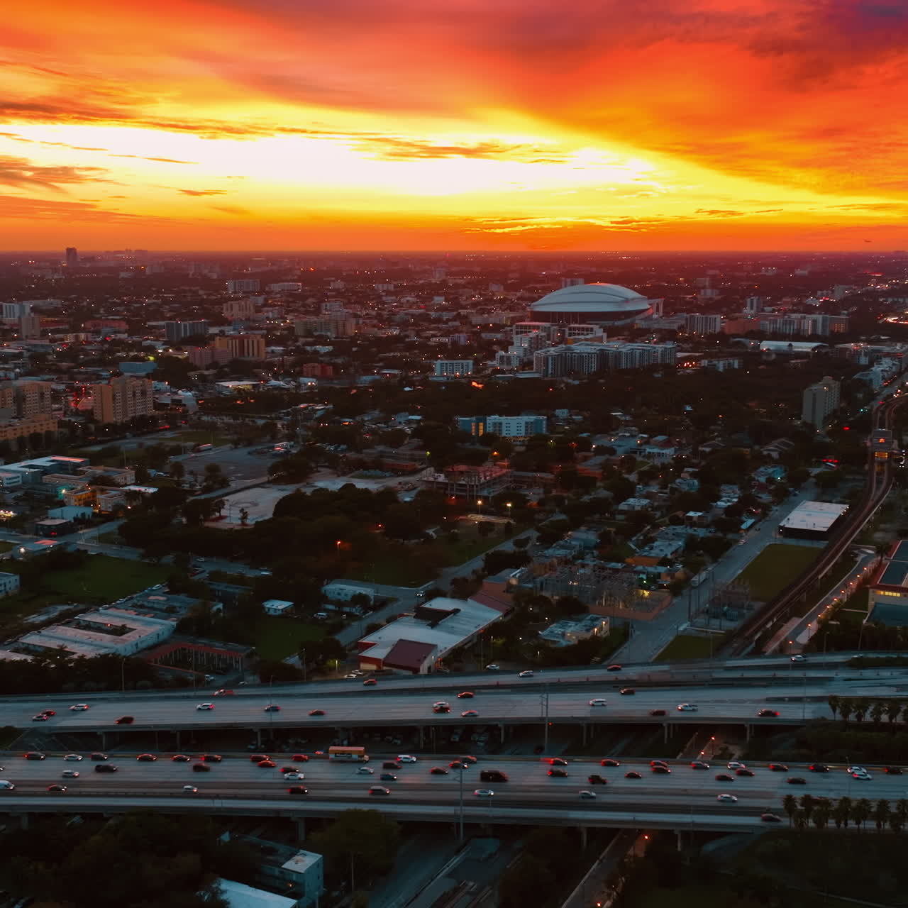 Fantastic yellow and orange sky above Miami panorama. Drone footage along the highways with heavy traffic.