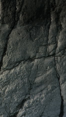 close up of a gray and black rock with cracks