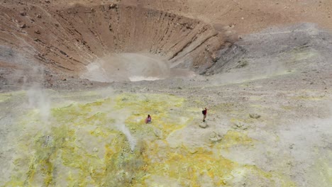 excursionistas masculinos y femeninos que viajan de excursión en el volcán y caminando a través de humos sulfúricos. isla del volcán en sicilia
