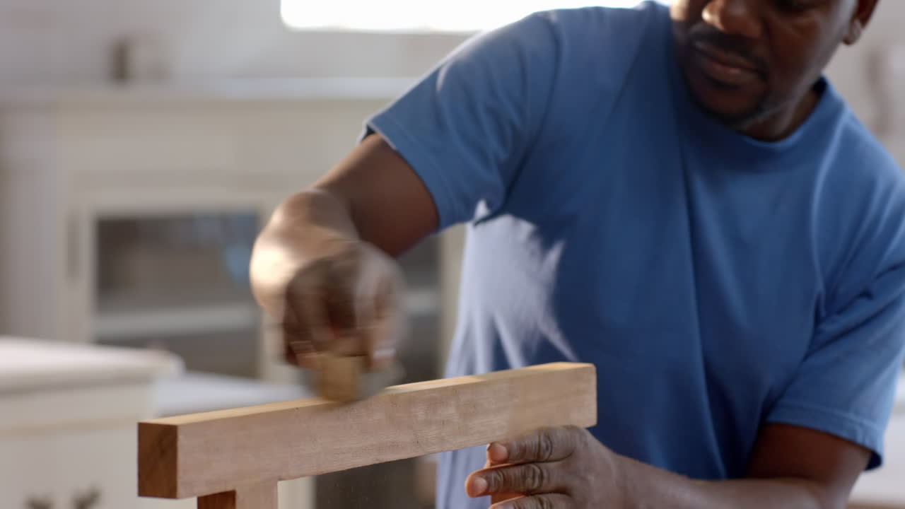 Inspecting wooden plank, African American man leaning in workshop, with safety goggles, copy space