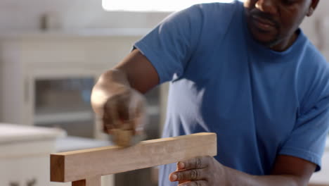inspecting wooden plank, african american man leaning in workshop, with safety goggles, copy space