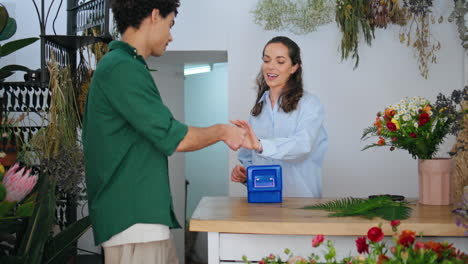 floristry business owner sell flowers. african customer pay money in plant store