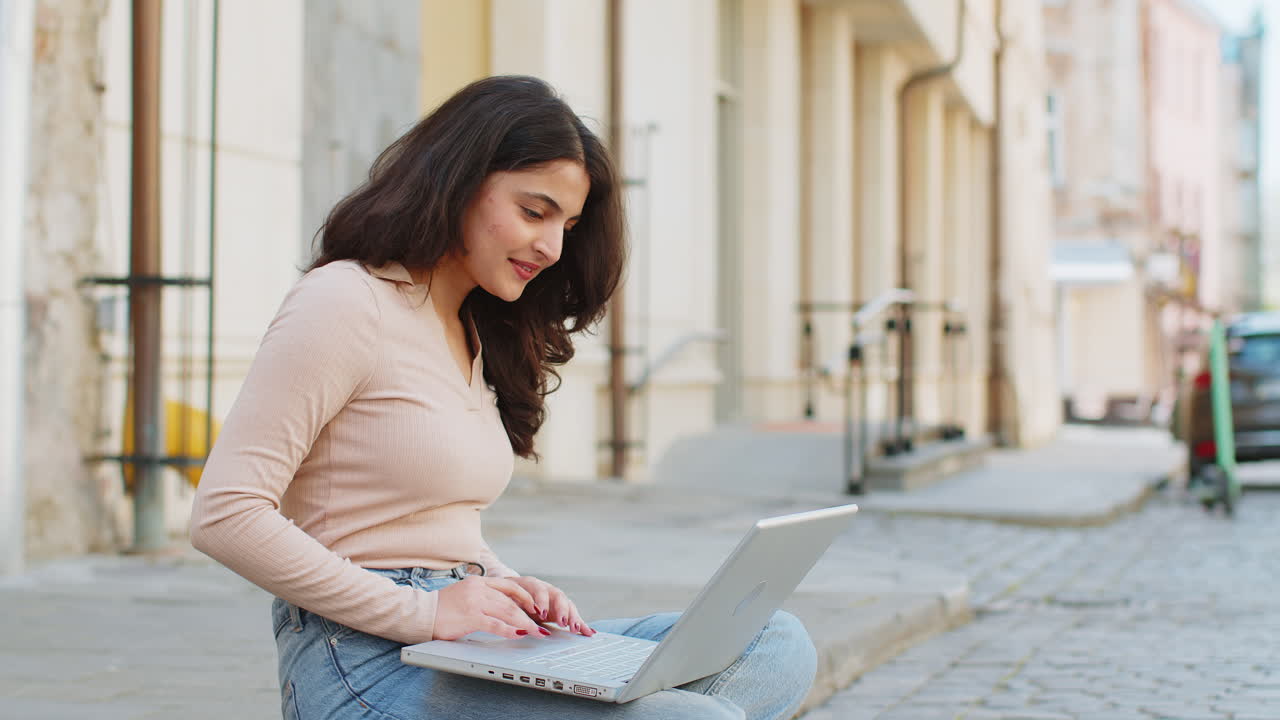mujer freelance trabajando en línea trabajo remoto con portátil sentado en la calle de la ciudad navegando por el sitio web
