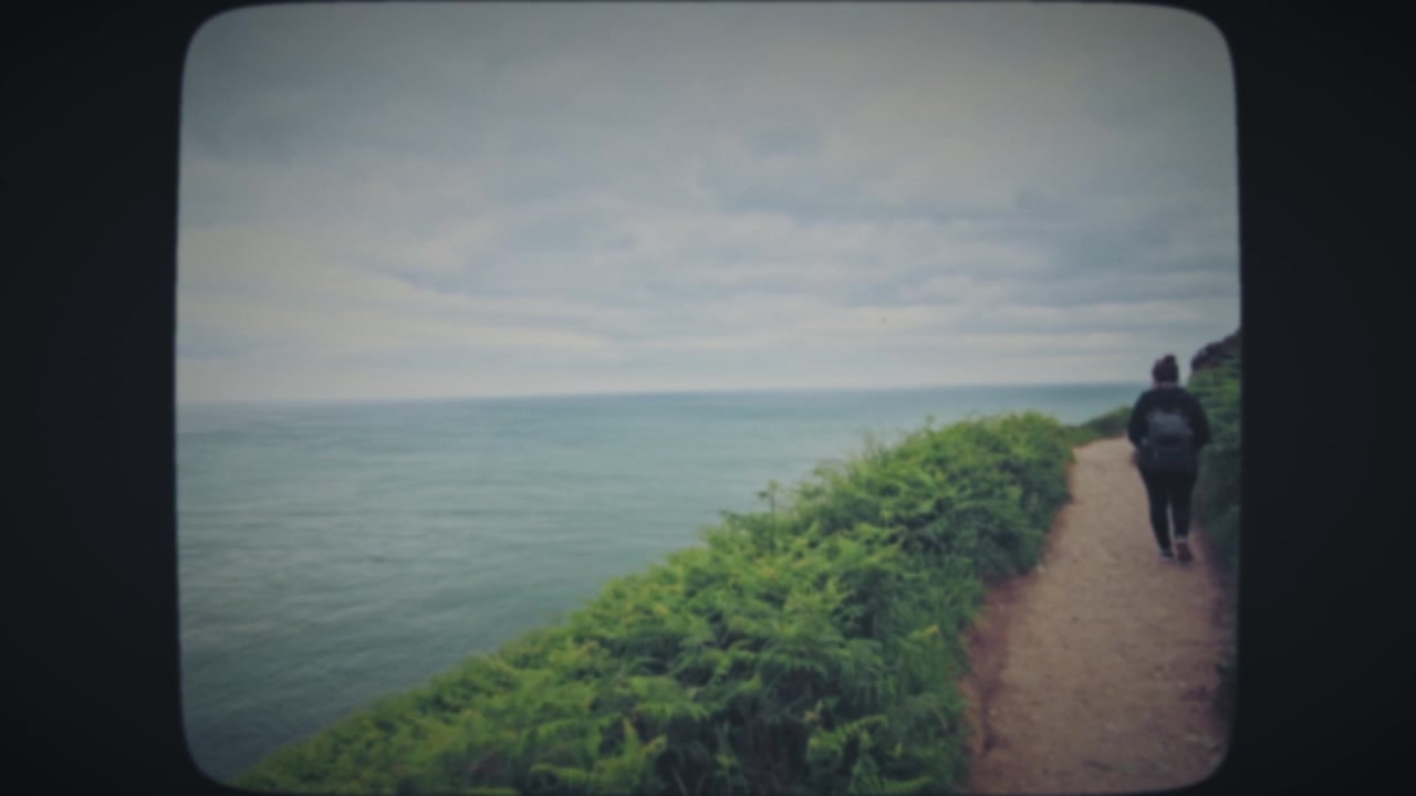 Woman walking along the cliff near ocean