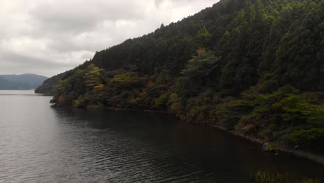 Aerial-drone-slide-reveal-out-on-moody-lake-with-forest-in-background