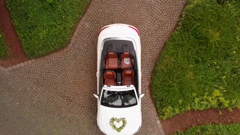 a drone rises above a wedding car that is located in the park