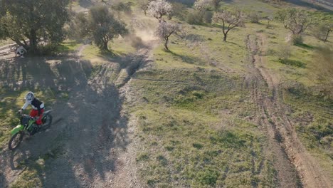 Static-aerial-drone-shot-from-a-motocross-track-in-Malaga-Spain-during-a-motocross-race-in-which-the-motorcyclists-perform-a-stunt-on-a-dusty-track-over-a-hill