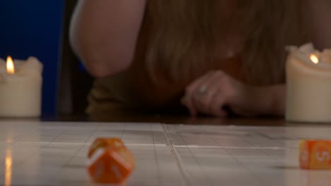 mujer lanza dados de rpg naranja a través de la alfombra de juego con una mano
