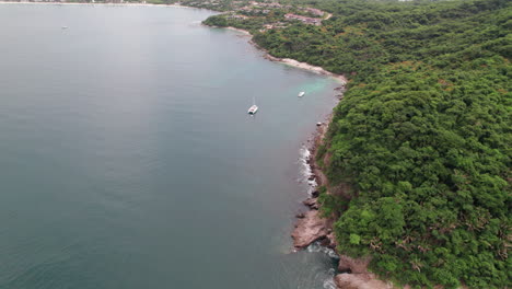 video de avión no tripulado de la costa de la playa de careyeros, que muestra la montaña rodeada por el mar con una vista angular de 45 grados, barco de pesca en acción