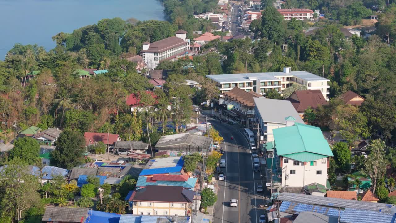 Flyover drone shot of Koh Chang's White Sand Beach, Thailand. Sunny morning over the village, sea, and lush greenery
