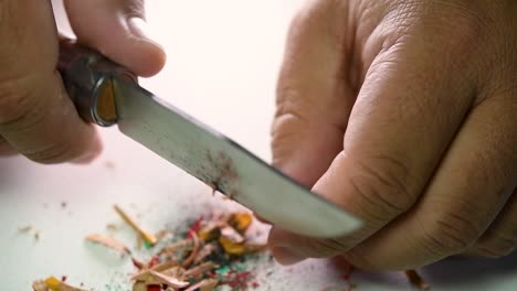 footage of hands slowly sharpening a pencil and some coloured pencils with a wedge pencil sharpener