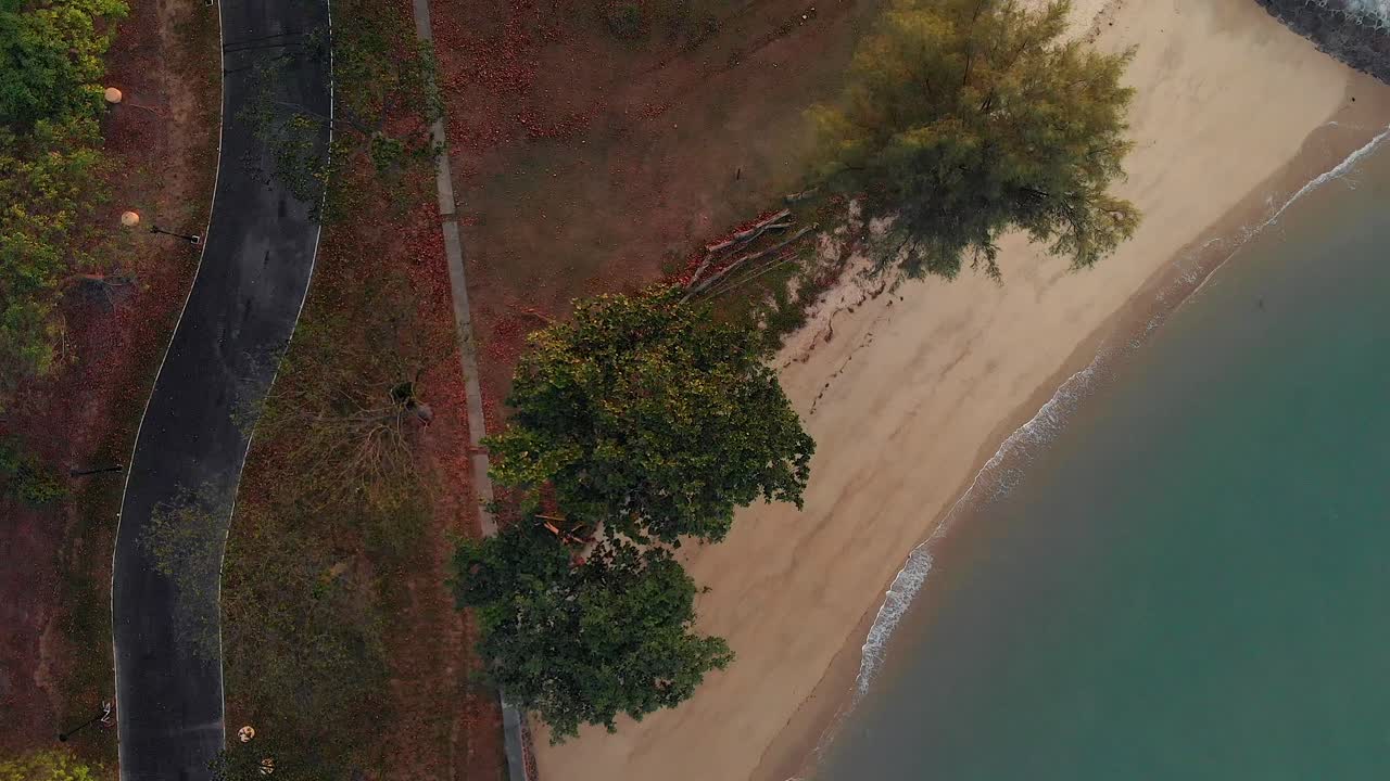 일출 동안 해변 위로 날아가는 하향식 드론 샷