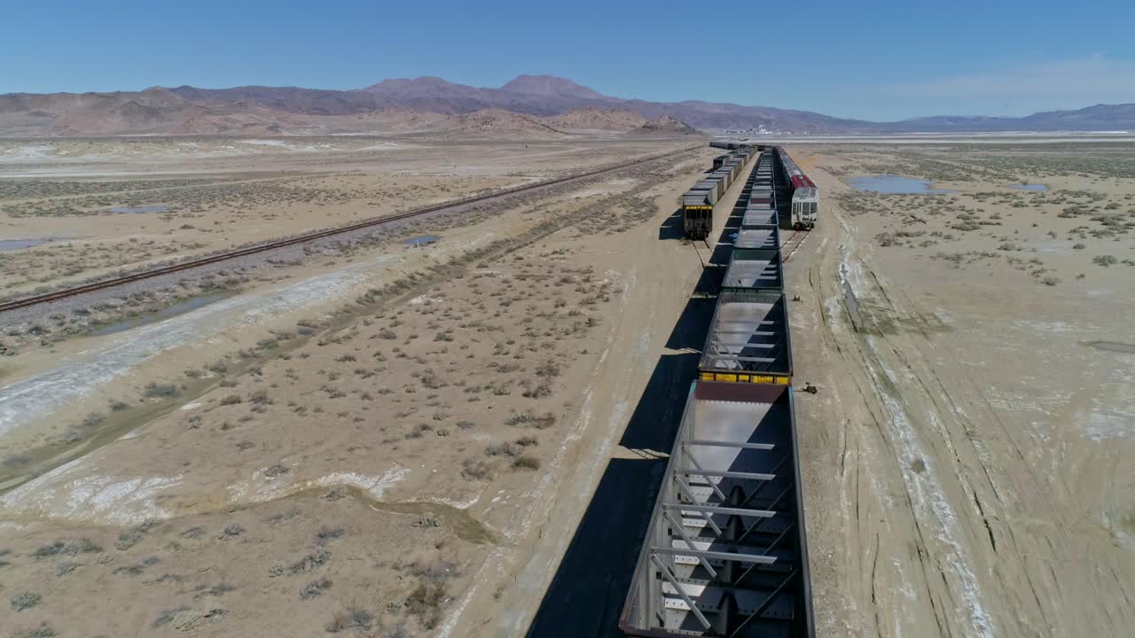 사막에 있는 3개의 병합 트랙에서 빈 기차 차량의 높은 오버헤드, 전방 모션 공중 보기