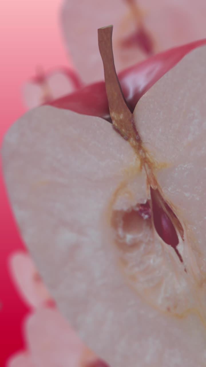 Close-up of a Sliced Red Apple with Seeds on a Pink Background