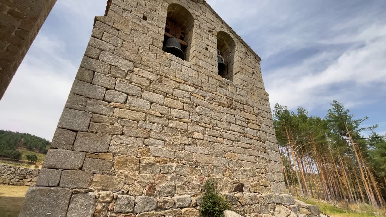 filming of a small bell tower made with granite blocks of different sizes where we can see with a camera elevation the two cavities for the bells finished in arches, bells of different sizes appear