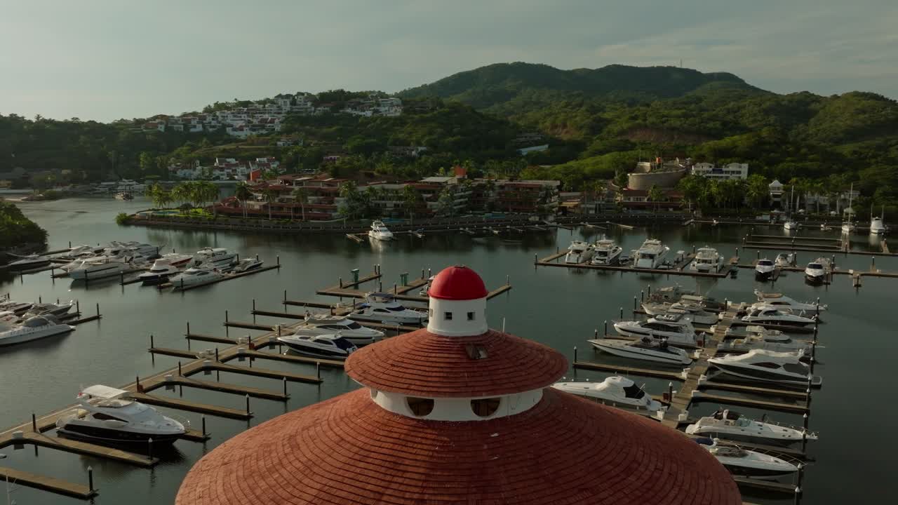 DRONE: (SUNSET) SLOW ORBIT WITH THE TOP PART OF THE LIGHT HOUSE AT THE MARINA OF IXTAPA, ZIHUATANEJO