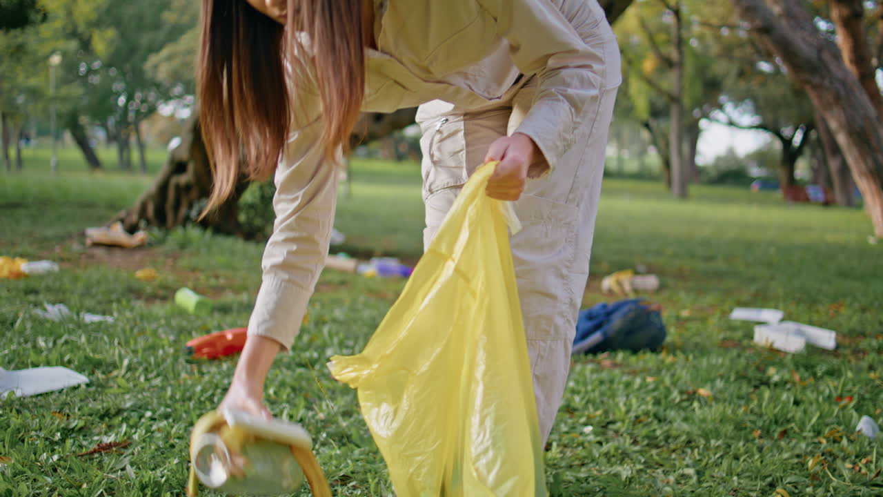 Volunteer woman taking litter in park concentrating at environmental cleanup.
